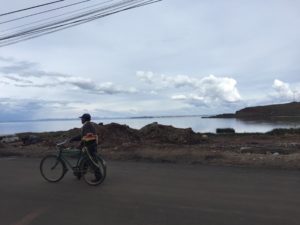 Peru Bolivia border - man walking with his bike with view from desaguadero in background