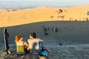 Sanboarders couple admiring the view off the top of sand dune