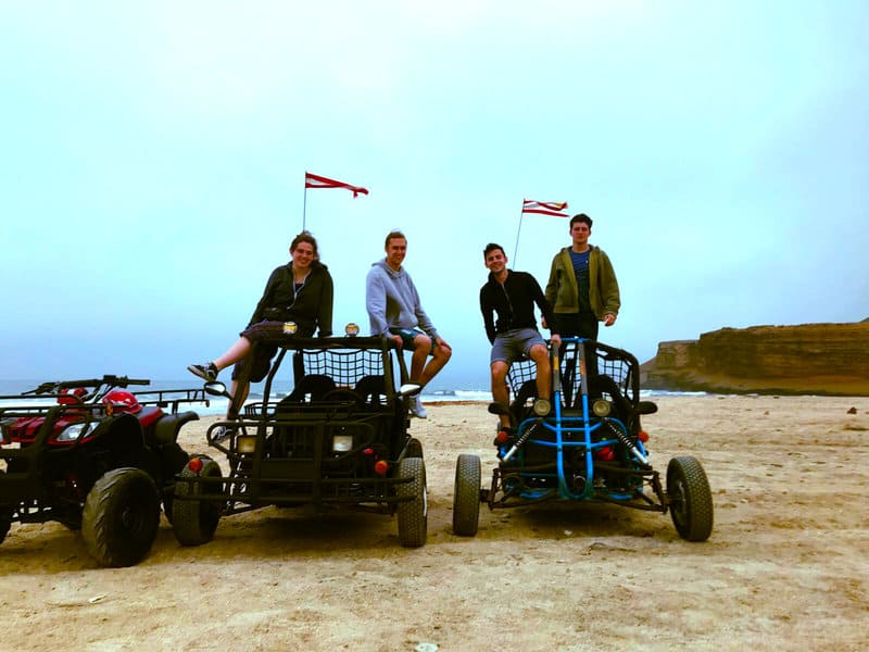 Four of us ATV riding Paracas quad bikes on beach in the Paracas National Reserve with sunset background