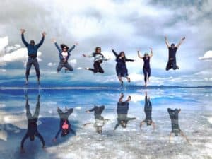 Group of travelers jumping at Bolivian salt flats after journey from Cusco to Uyuni